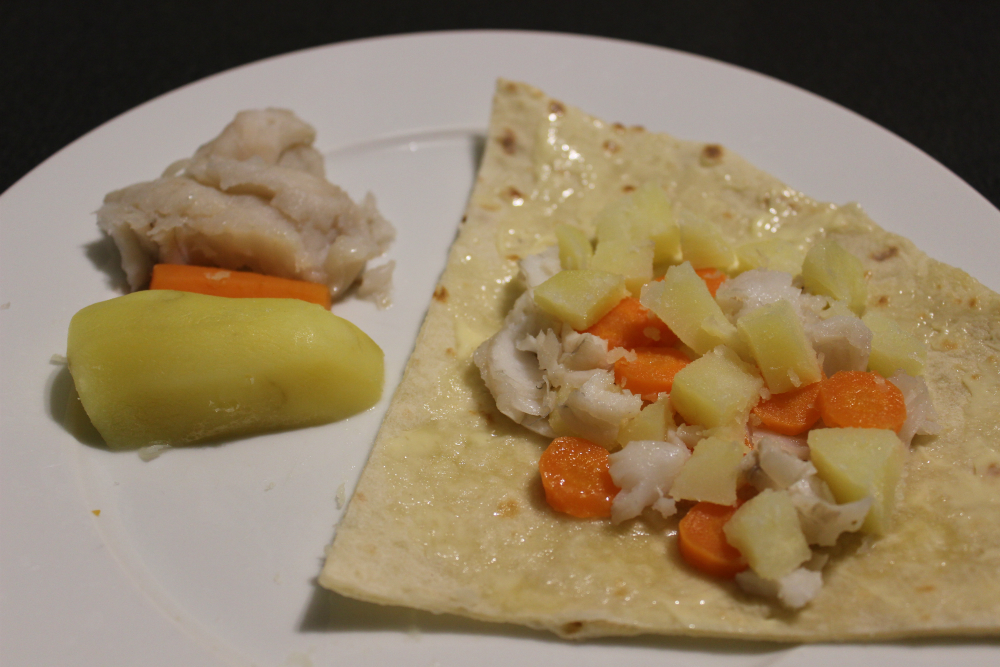 Biletet viser fisk og kling på ein tallerken. Mjukebrød med smør, kvitfisk, potet og gulrot.